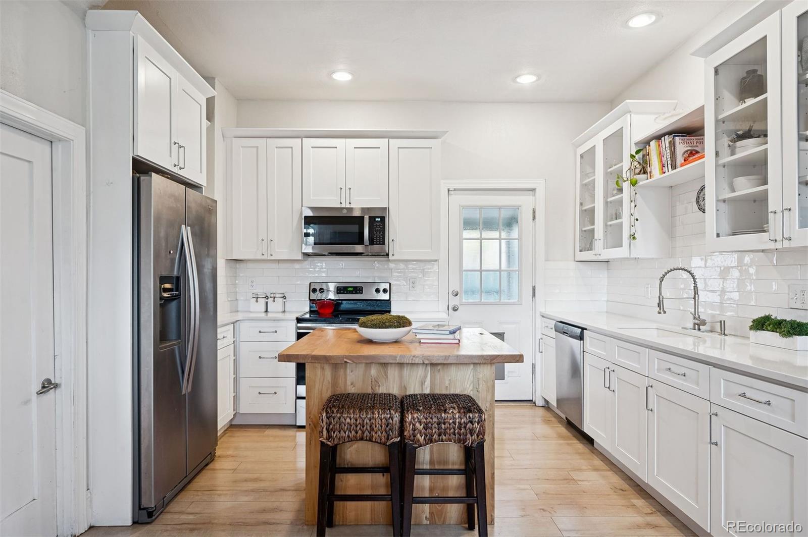 2109 West 41st Avenue Denver, CO 80211 - Photo 13 of 33 a kitchen with stainless steel appliances a sink stove refrigerator and cabinets
