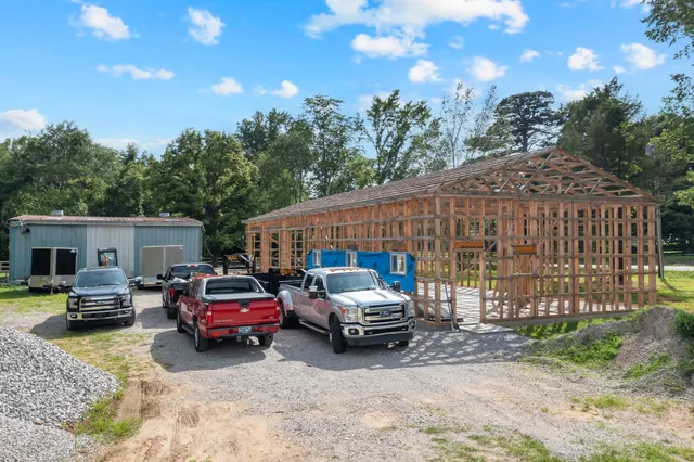 a view of a patio with a table and chairs under an umbrella with large trees