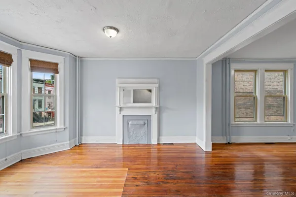 a view of an empty room with window and wooden floor