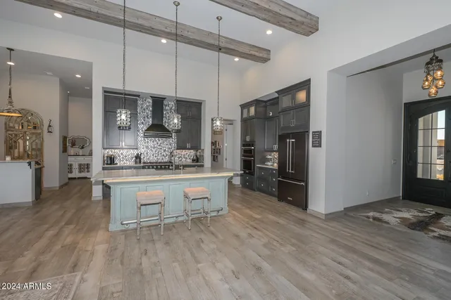 a open kitchen with stainless steel appliances granite countertop a refrigerator a stove and a wooden floors