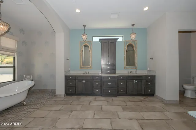 a bathroom with a granite countertop double vanity sink a mirror and a bathtub