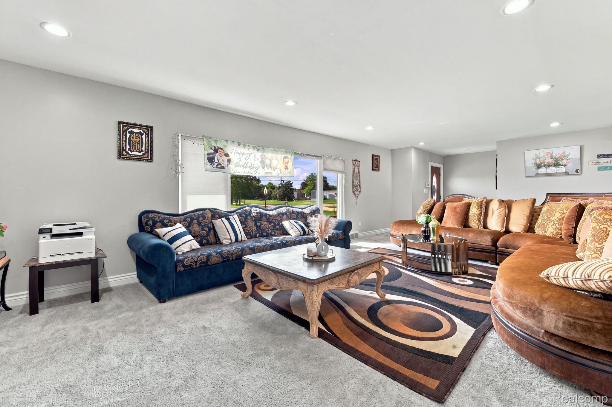 5353 18 Mile Road Sterling Heights, MI 48314 - Photo 12 of 53 Recessed lighting illuminates a spacious living area featuring light gray wall paint and gray carpeting