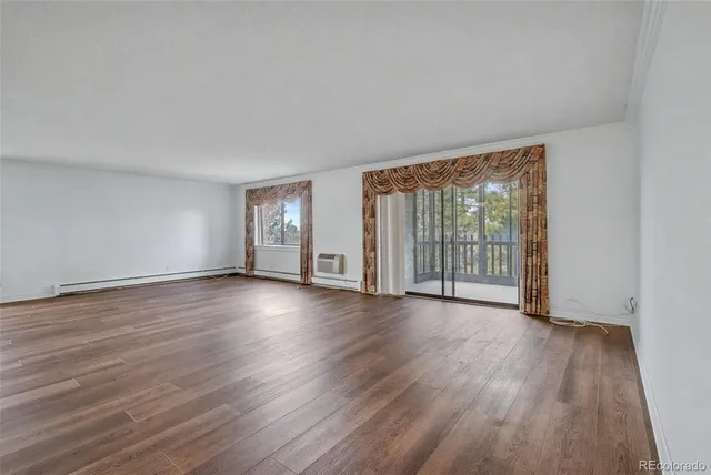a view of an empty room with wooden floor and glass door