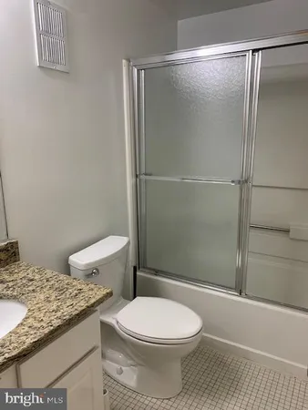 a bathroom with a granite countertop toilet and a shower