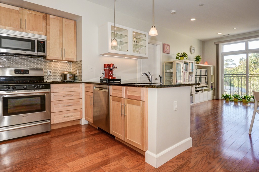 a kitchen with kitchen island granite countertop a stove top oven a sink a counter space and wooden floor