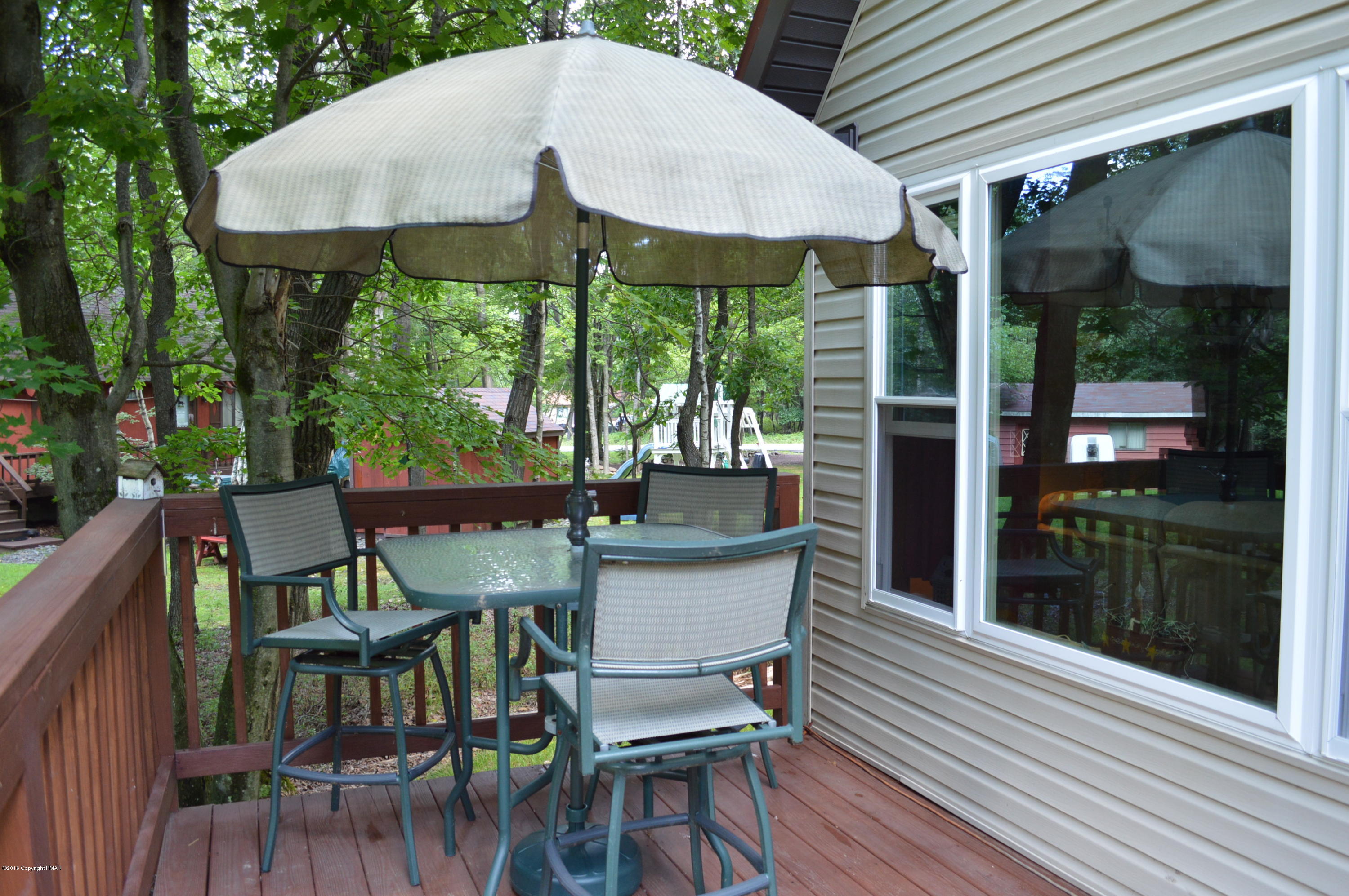 256 Fern Ridge Road Blakeslee, PA 18610 - Photo 21 of 27 a view of a patio with table and chairs under an umbrella with wooden floor