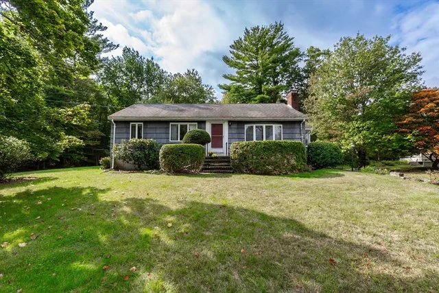 a front view of a house with a yard and trees