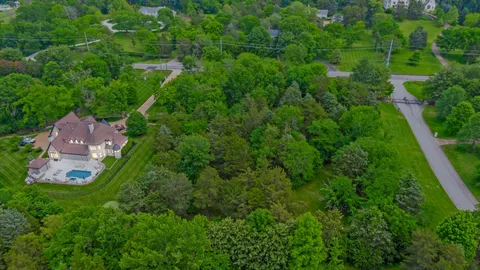 an aerial view of residential house with outdoor space and trees all around