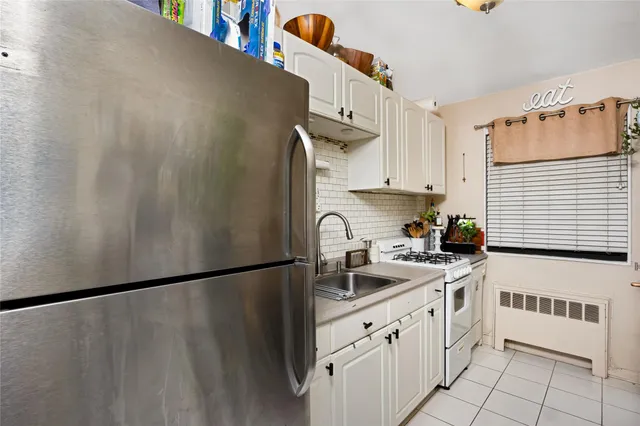a kitchen with granite countertop a sink a stove a refrigerator and cabinets