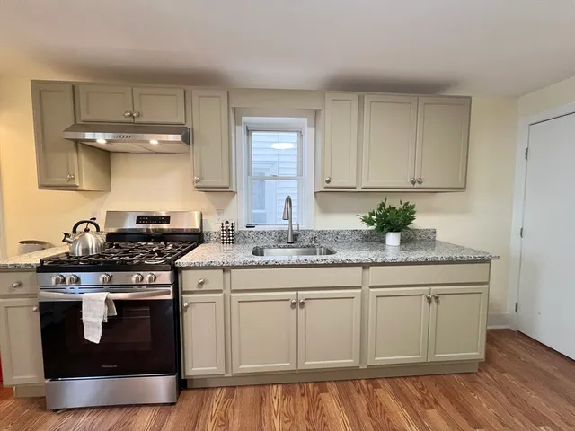 a kitchen with stainless steel appliances granite countertop a stove a sink and white cabinets