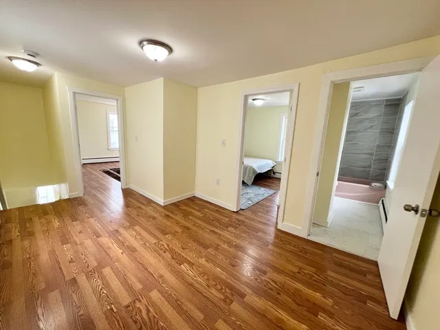 a view of a hallway with wooden floor and a bathroom