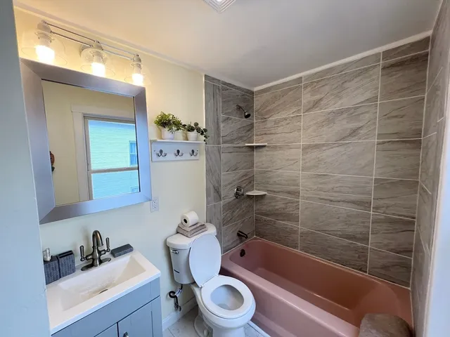 a bathroom with a bathtub shower sink mirror vanity and toilet