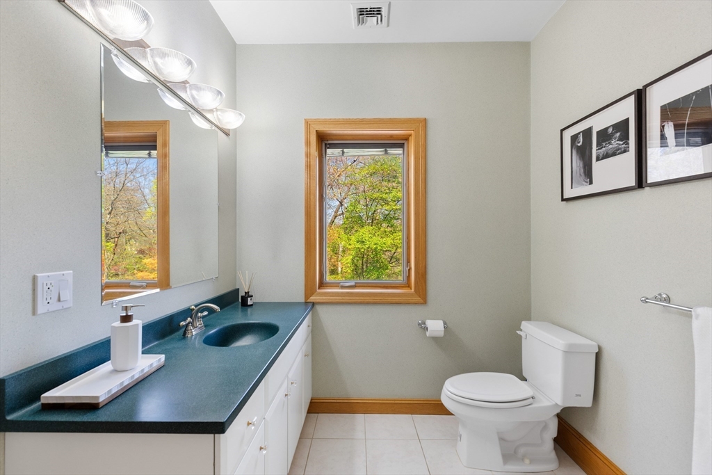16 Solomon Pierce Road Lexington, MA 02420 - Photo 30 of 42 a bathroom with a granite countertop sink a toilet a mirror and a window