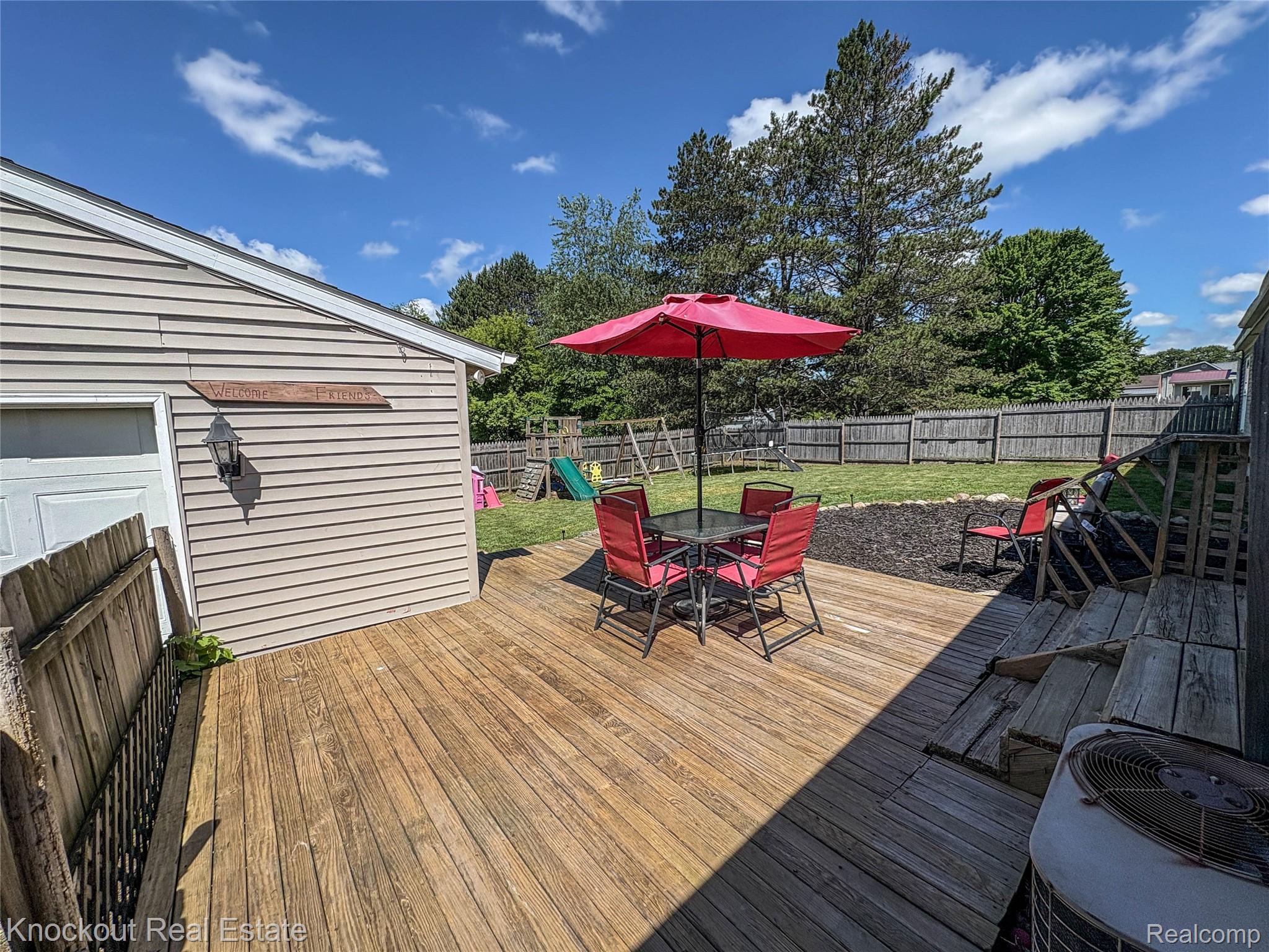7760 Bell Road Birch Run, MI 48415 - Photo 55 of 68 Expansive wood deck with stairs leading to a spacious backyard featuring a privacy fence and mature trees