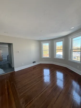 a view of an empty room with wooden floor and a window
