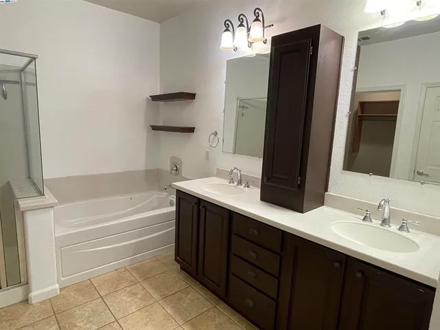 a bathroom with a double vanity sink mirror and bathtub