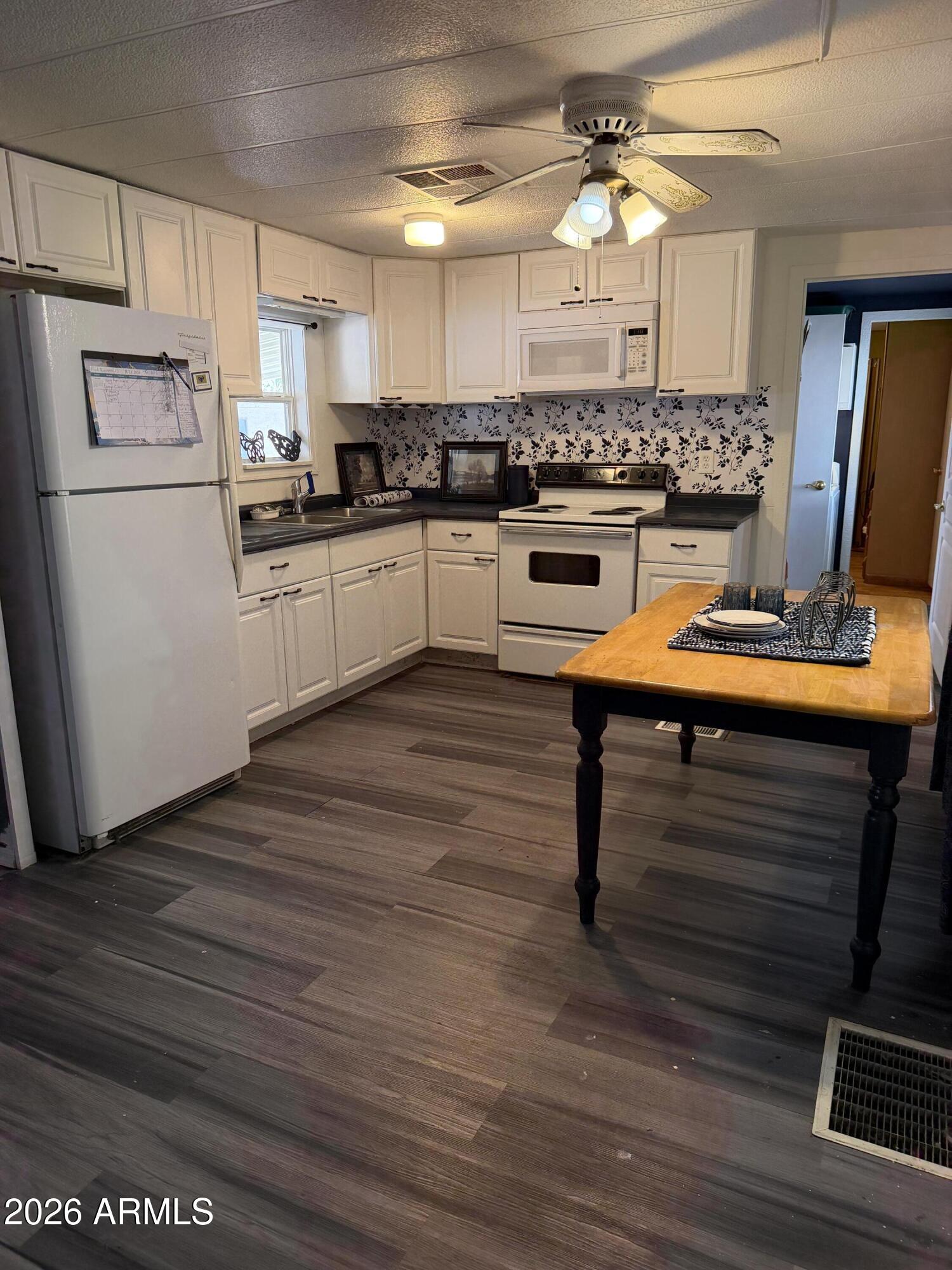 126 South Tomahawk Road, Unit 5 Apache Junction, AZ 85119 - Photo 13 of 14 a kitchen with stainless steel appliances kitchen island granite countertop a stove a refrigerator and a dining table with wooden floor