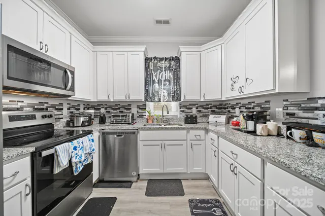 a kitchen with stainless steel appliances granite countertop a sink a stove and cabinets