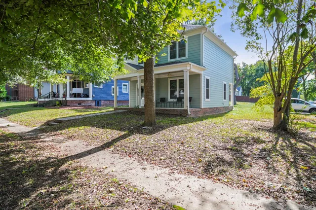 a view of a house with a yard and large tree