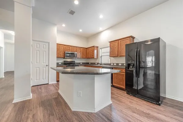 a kitchen with stainless steel appliances granite countertop a refrigerator stove and wooden floor