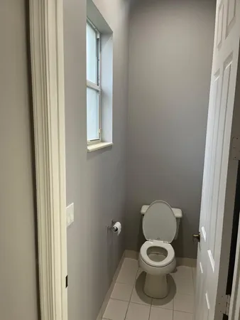 a white toilet sitting in a bathroom next to a window