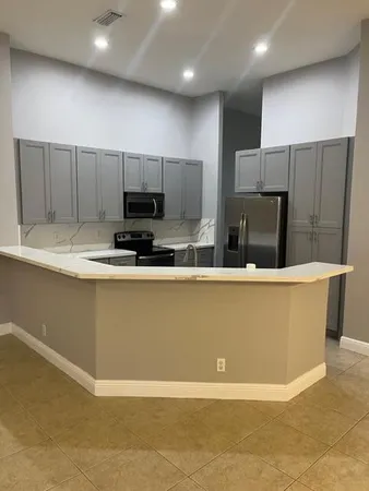 a view of kitchen with stainless steel appliances granite countertop a stove a sink a refrigerator and white cabinets with wooden floor
