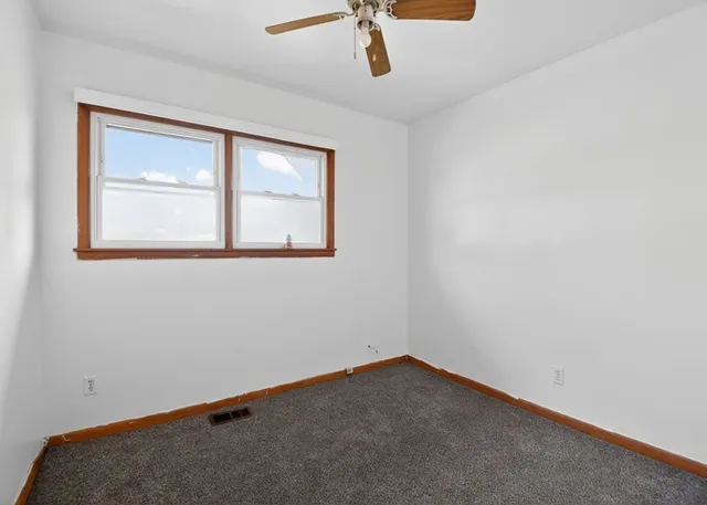 an empty room with a window and a ceiling fan