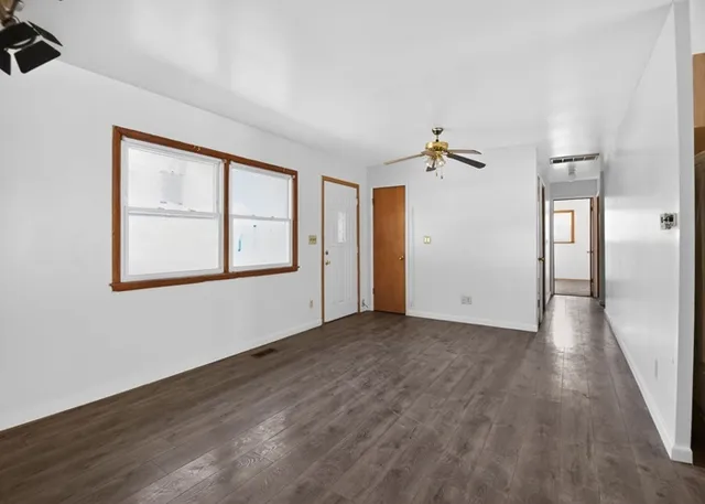 a view of an empty room with a window and wooden floor