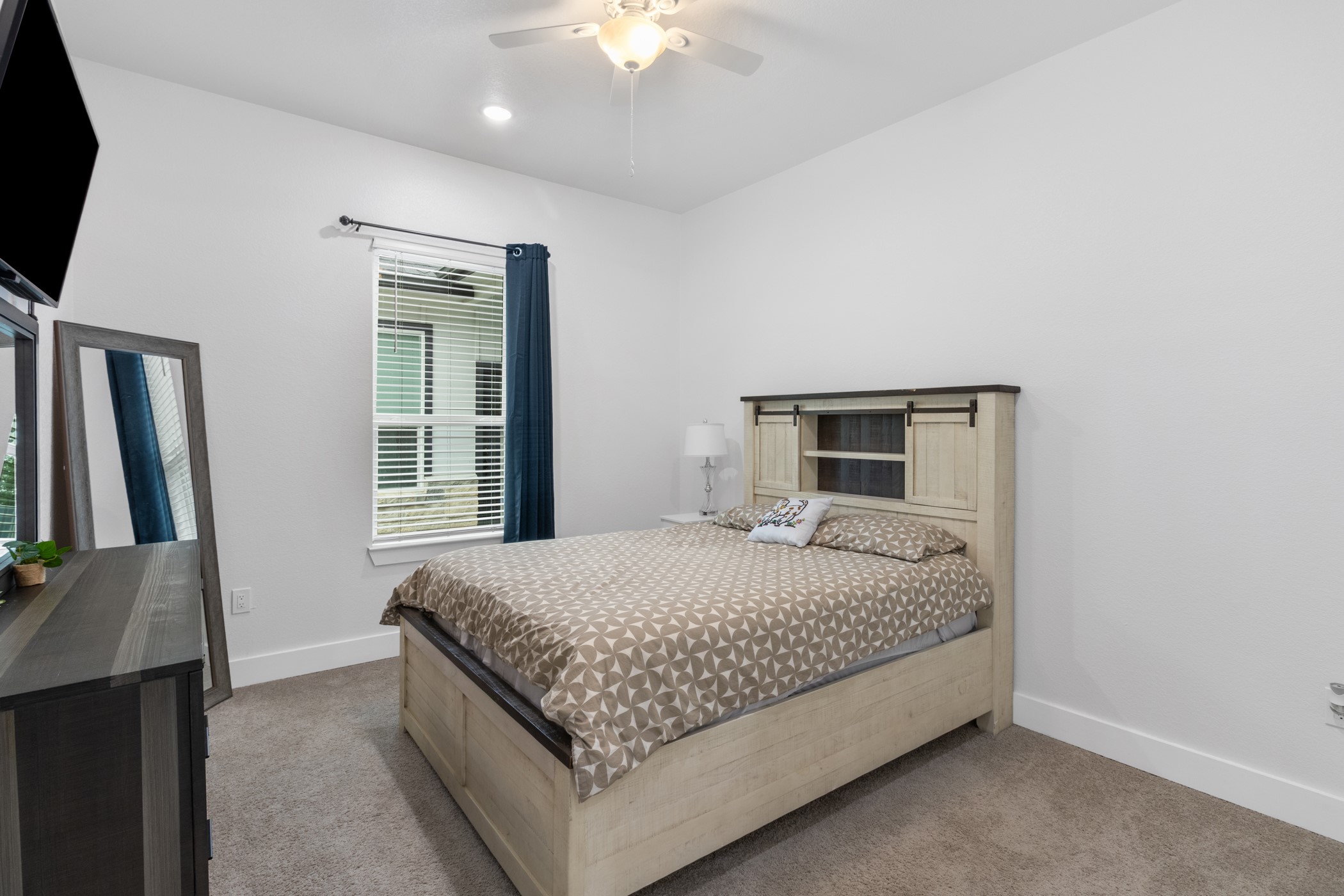 123 Zacate Street Elgin, TX 78621 - Photo 17 of 33 Neutral color palette bedroom featuring carpet flooring, crisp white walls, and a ceiling fan with integrated lighting