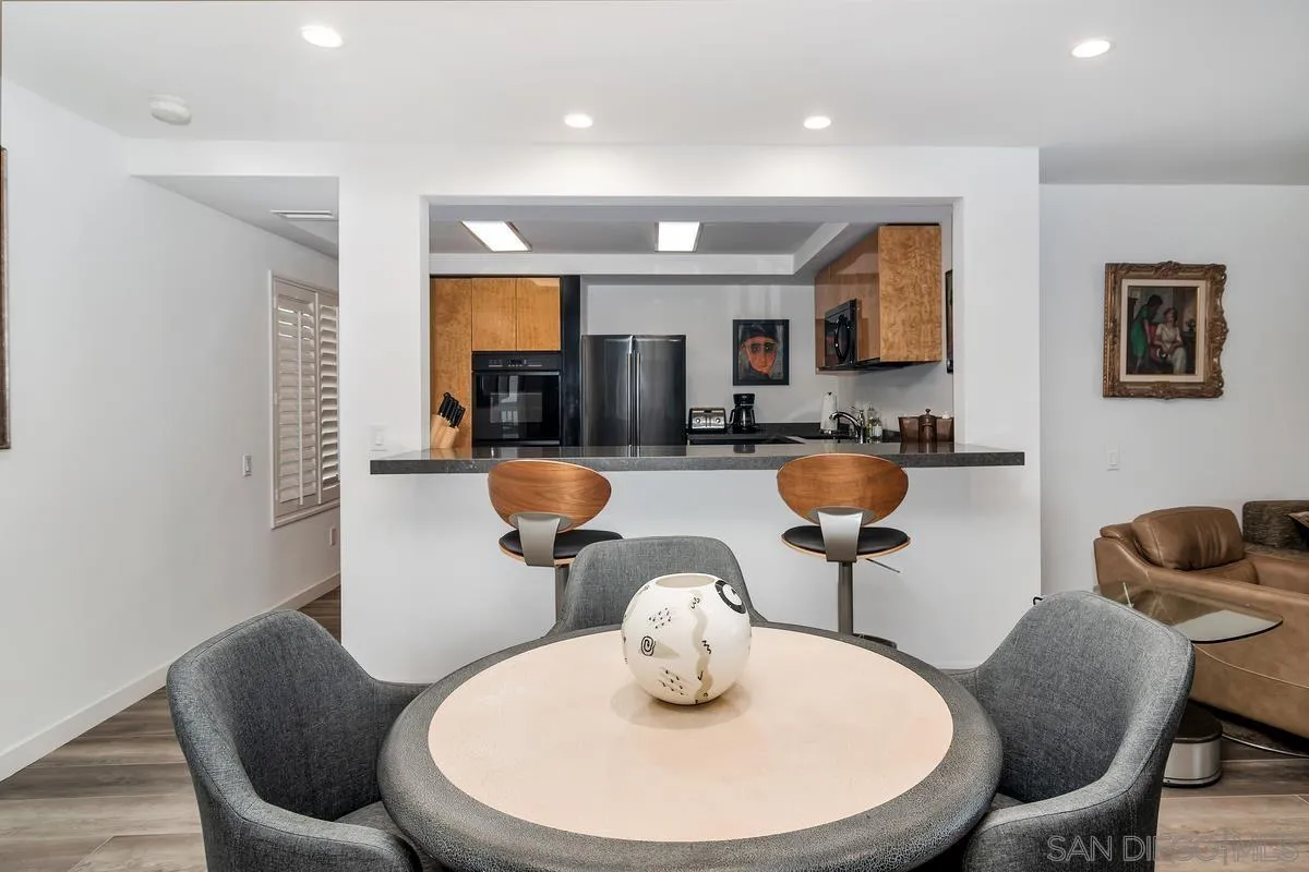 100 Coast Boulevard, Unit 304 La Jolla, CA 92037 - Photo 11 of 36 a kitchen with stainless steel appliances dining table a sink and a refrigerator