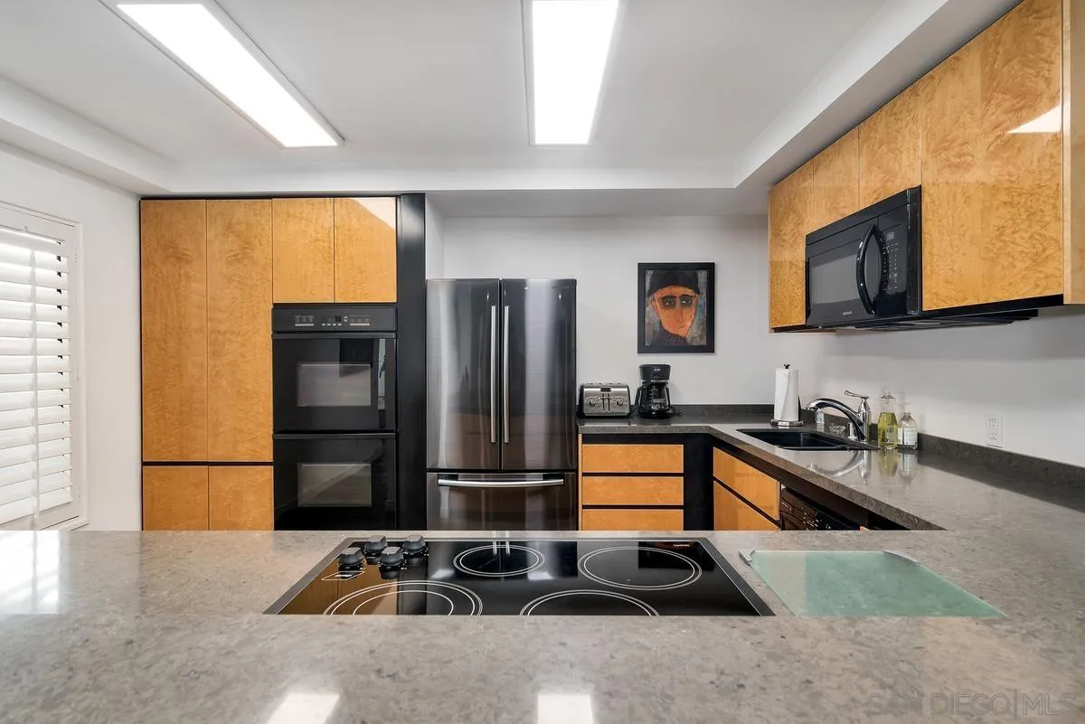 100 Coast Boulevard, Unit 304 La Jolla, CA 92037 - Photo 12 of 36 a kitchen with granite countertop a refrigerator and a sink