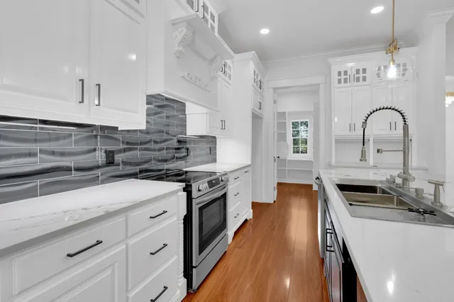 a kitchen with stainless steel appliances granite countertop a sink a stove top oven a counter space and cabinets