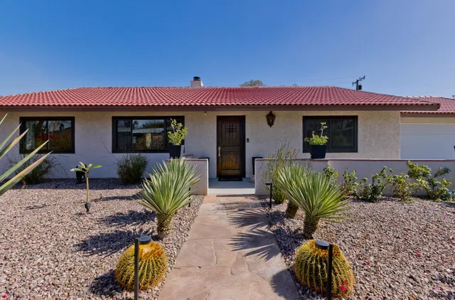 a view of a house with a yard and potted plants