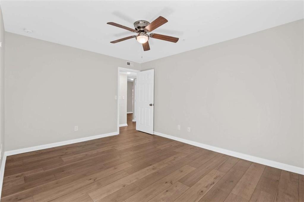 1166 Booth Road, Unit 407 Marietta, GA 30008 - Photo 14 of 18 an empty room with wooden floor ceiling fan and window