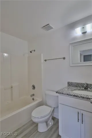 a bathroom with a granite countertop toilet a sink and a bathtub