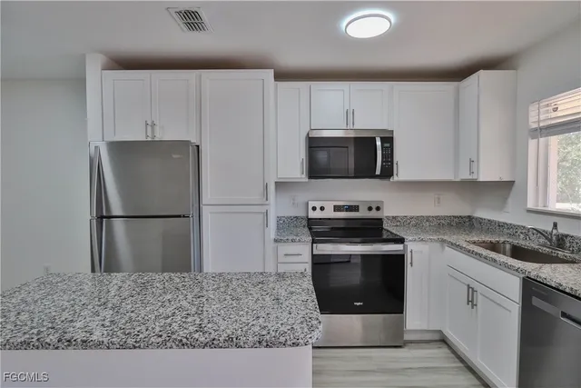 a kitchen with stainless steel appliances granite countertop a stove a refrigerator and a sink