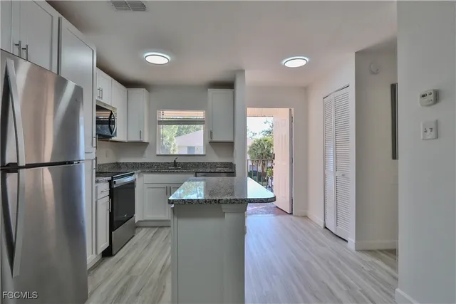 a kitchen with stainless steel appliances granite countertop a refrigerator a stove and a sink