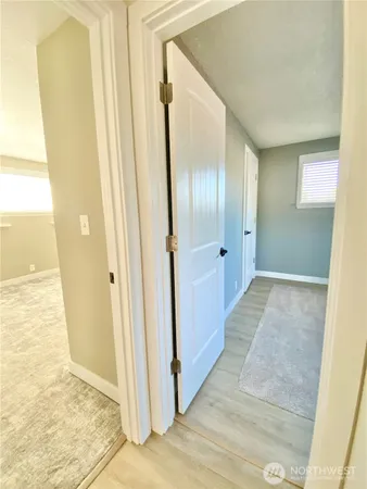 a view of a hallway with wooden floor and a bathroom