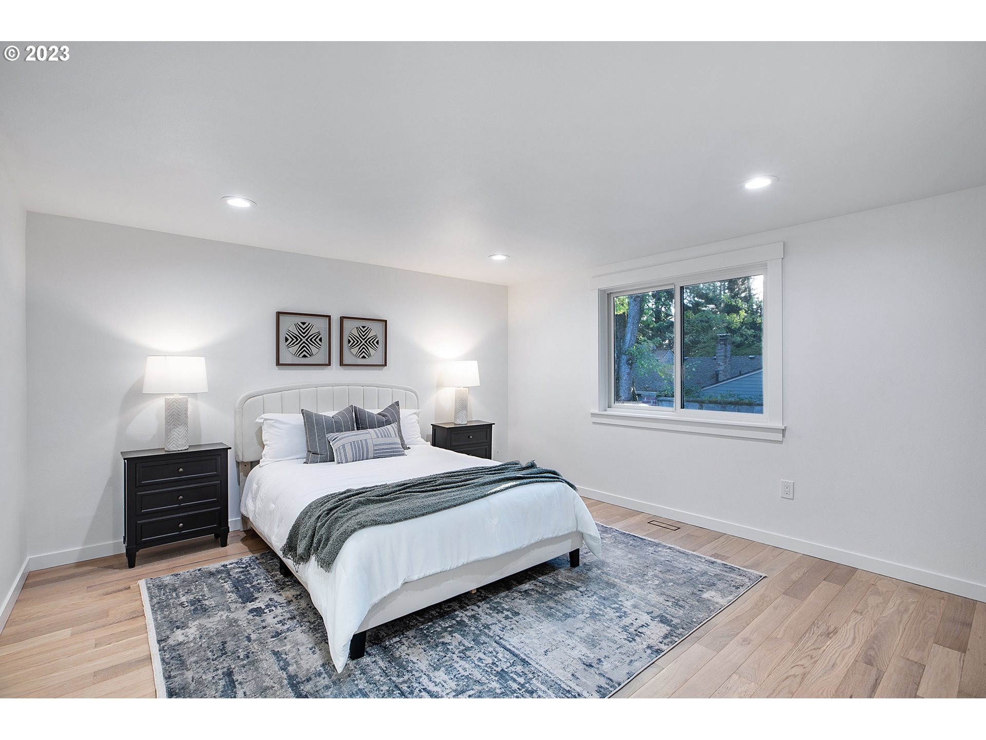 9906 Northwest Leahy Road Portland, OR 97229 - Photo 20 of 36 a bedroom with a large bed and a wooden floor