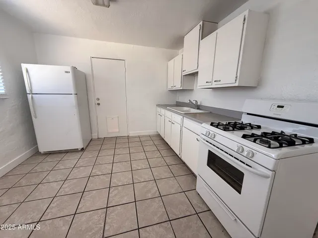 a kitchen with a stove a refrigerator and white cabinets