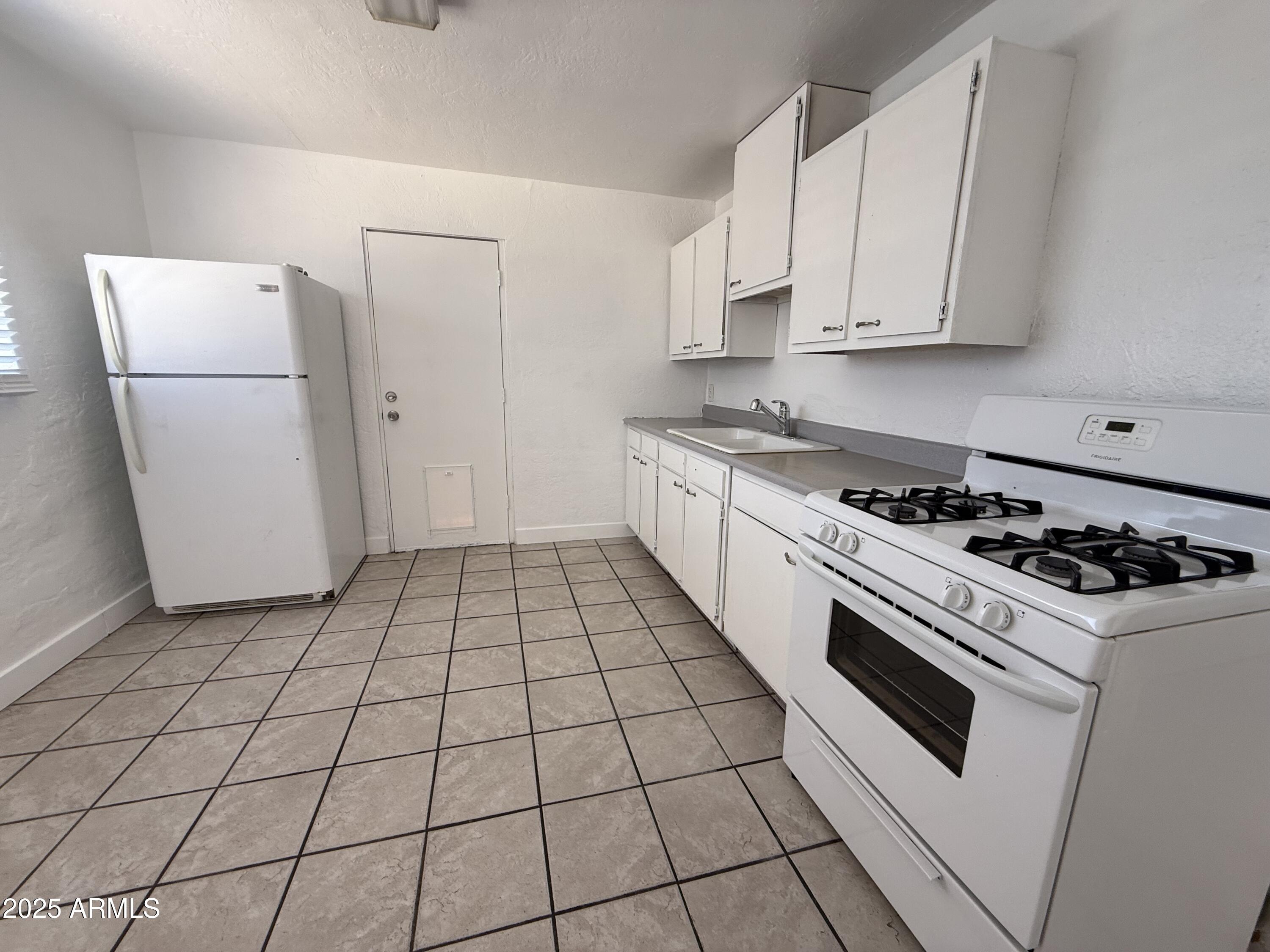 7532 North 21st Avenue, Unit 1 Phoenix, AZ 85021 - Photo 14 of 19 a kitchen with a stove a refrigerator and white cabinets