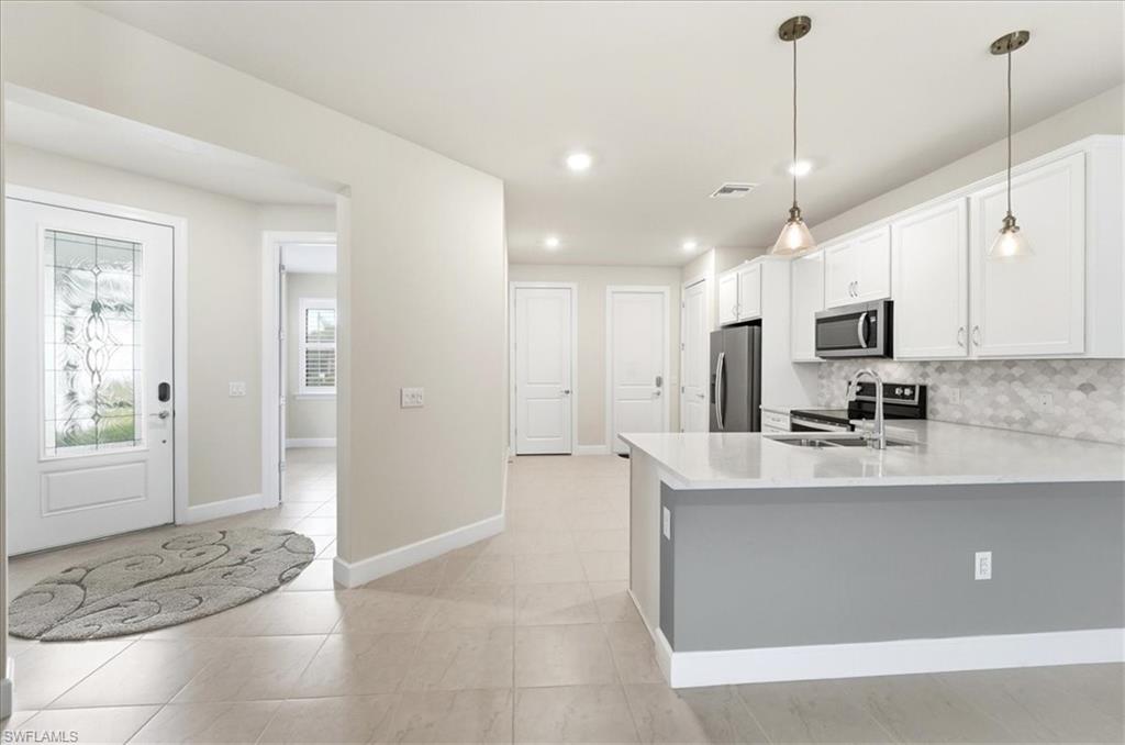 5935 Mayflower Way Ave Maria, FL 34142 - Photo 5 of 36 a large kitchen with kitchen island a sink stainless steel appliances and cabinets