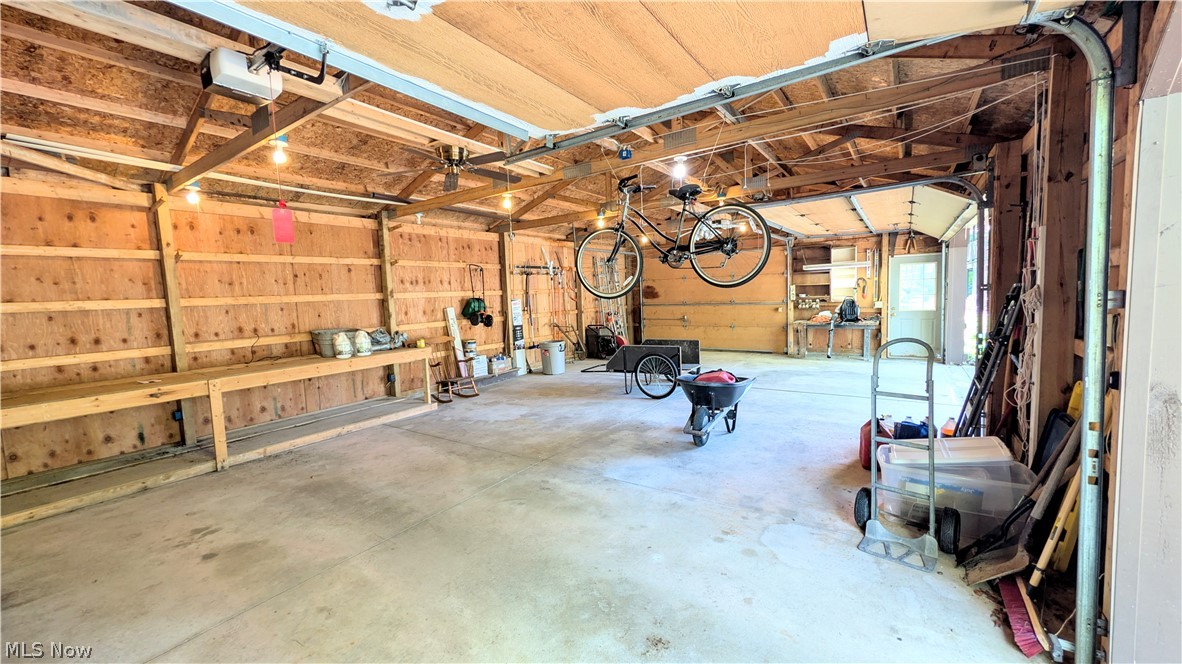 6409 Old Woods Road Ashtabula, OH 44004 - Photo 30 of 43 Spacious garage featuring a concrete floor, exposed wood framing, built-in shelving, two overhead garage doors, and an additional pedestrian door