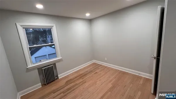 a view of hallway with window and wooden floor