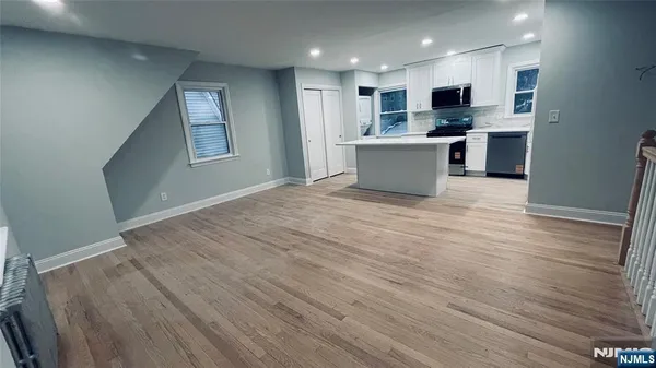 a view of kitchen with kitchen island a sink wooden floor and a refrigerator