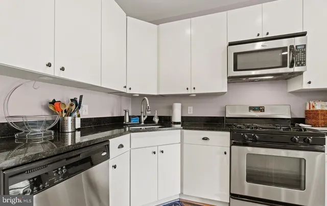 a kitchen with granite countertop white cabinets and black appliances