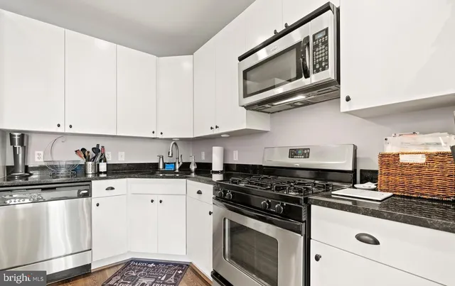 a kitchen with granite countertop white cabinets stainless steel appliances and a sink