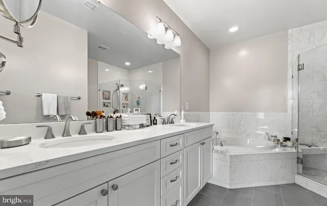 a bathroom with a double vanity sink mirror and bathtub