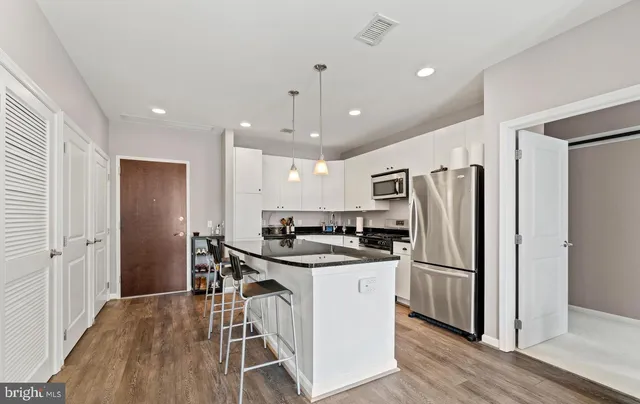 a kitchen with stainless steel appliances a refrigerator a stove a sink cabinets and wooden floor