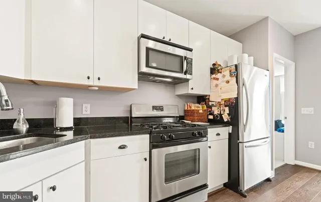 a kitchen with white cabinets and stainless steel appliances